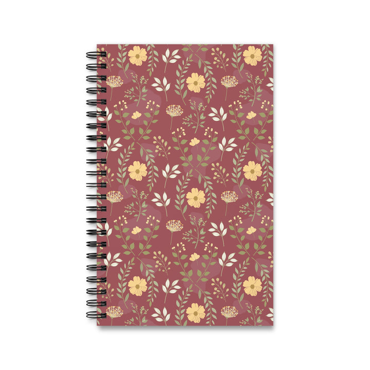 A spiral-bound notebook with a dusty rose cover decorated with a repeating floral pattern of yellow flowers and green leaves, shown on a plain white background.