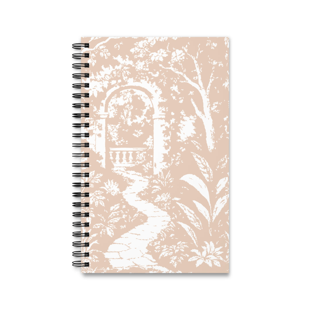 A spiral-bound notebook with a beige and white toile-style garden design, featuring a white arched gate, path, and foliage on a light beige background, shown on a plain white background.