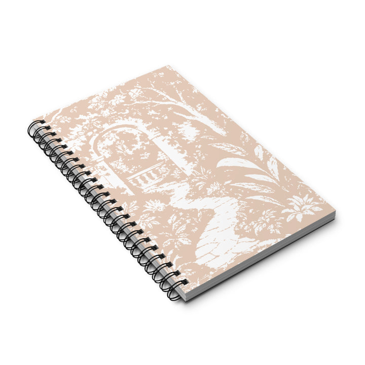 A spiral-bound notebook with a beige cover featuring a white toile-style pattern of a garden archway and foliage, shown on a clean white background.