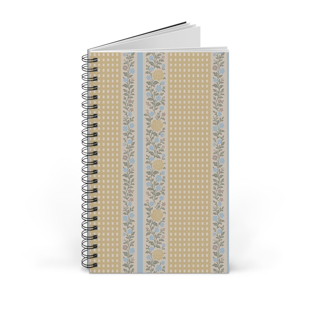 A spiral-bound notebook with a decorative cover featuring vertical stripes of beige gingham, light blue gingham, and a floral pattern in muted blue and yellow, shown on a white background.