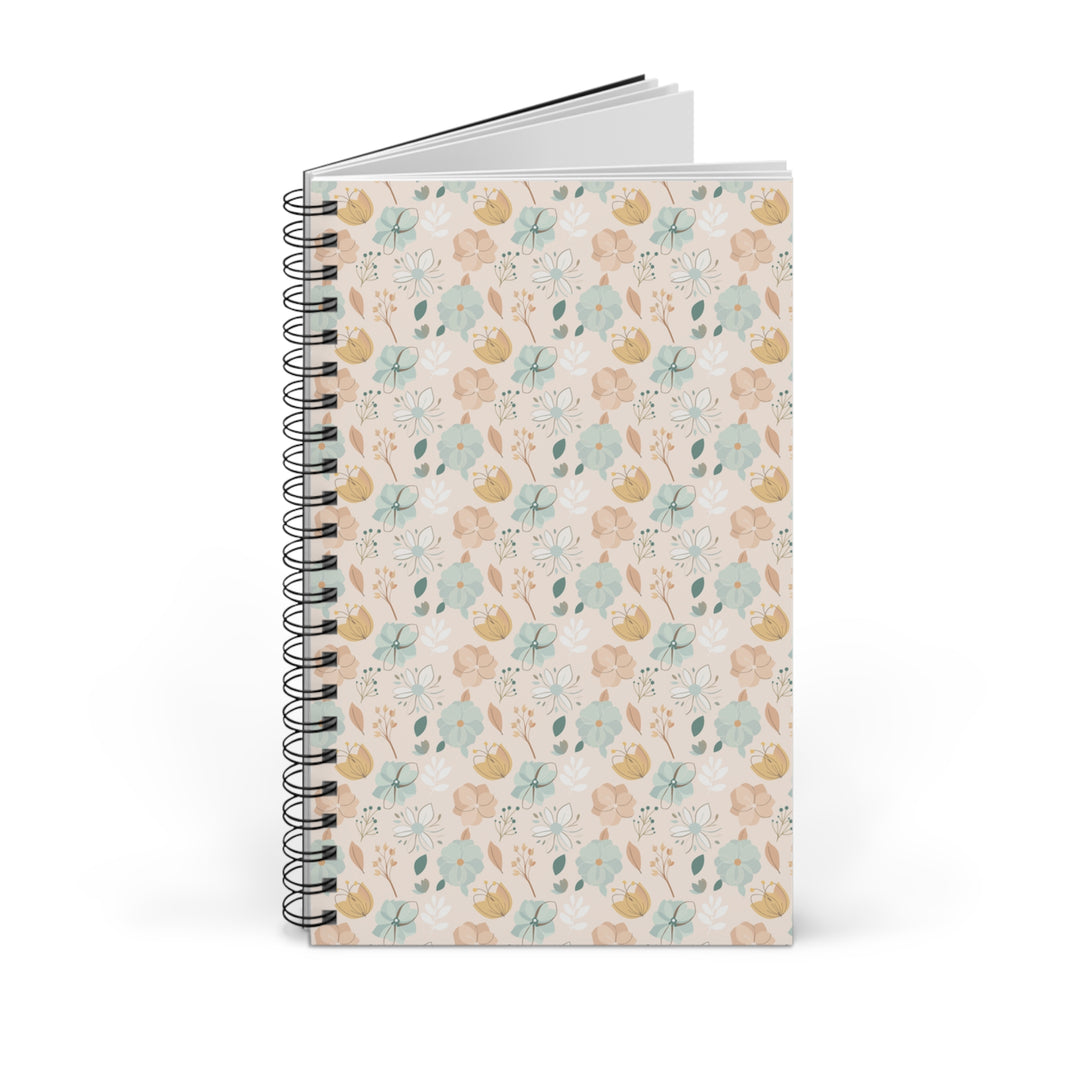 A spiral-bound notebook with a delicate floral pattern on the cover, standing upright against a clean white background.