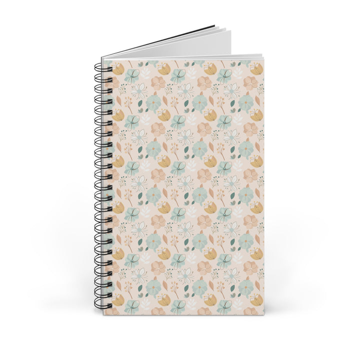 A spiral-bound notebook with a delicate floral pattern on the cover, standing upright against a clean white background.