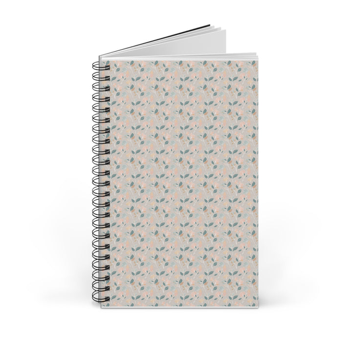 A spiral-bound notebook with a light beige cover decorated in a delicate repeating pattern of small pink flowers and green leaves, shown on a clean white background.