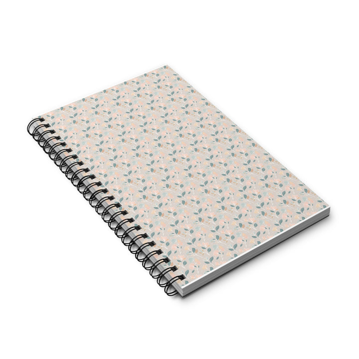 A spiral-bound notebook with a light beige cover decorated with a delicate, small-scale floral and leaf pattern in soft pink and muted green, shown on a clean white background.