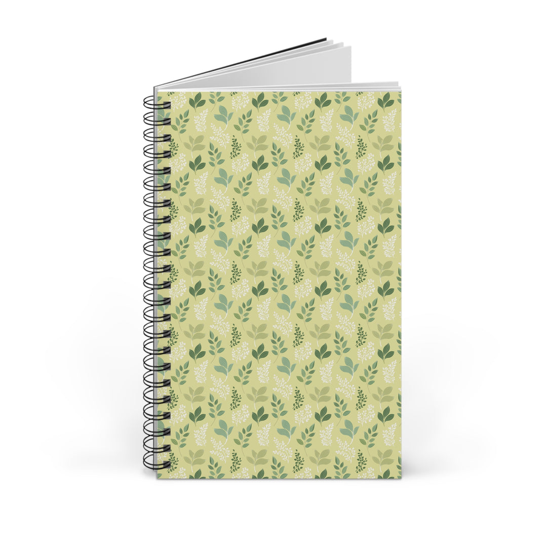 A spiral-bound notebook with a light green cover featuring a repeating pattern of darker green leaves, shown on a plain white background.