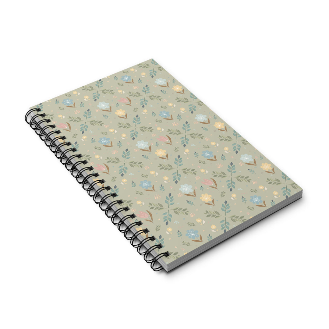 A spiral-bound notebook with a light sage green cover decorated with a delicate pattern of small flowers, leaves, and butterflies in soft pastel shades of blue, pink, yellow, and green. The notebook is shown at an angle on a clean white background.