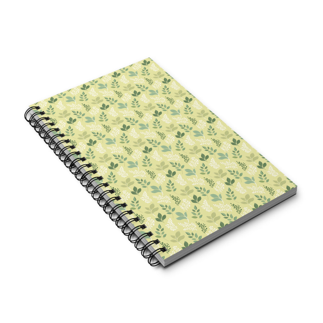 A spiral-bound notebook with a light yellow-green cover decorated with a repeating pattern of green leaves and small white birds, shown on a clean white background.