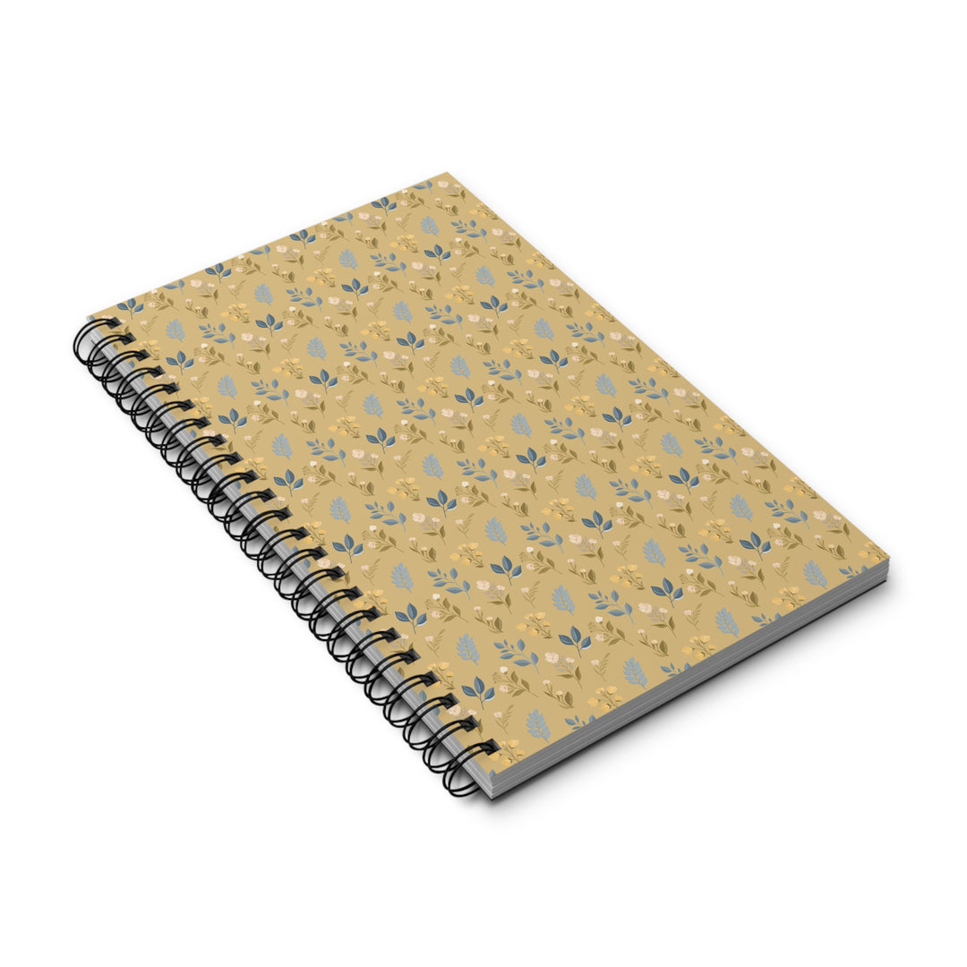A spiral-bound notebook with a tan cover featuring a repeating light blue and white floral pattern, shown at an angle on a white background.