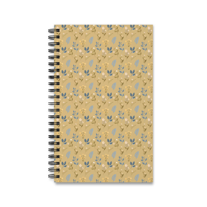 A spiral-bound notebook with a tan cover featuring a repeating pattern of small blue and yellow botanical illustrations, shown on a plain white background.
