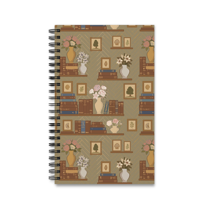 A spiral-bound notebook with a vintage-style bookshelf pattern on the cover, featuring brown books, vases with pink and white flowers, and framed art on a beige background.