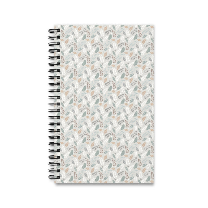 A spiral-bound notebook with a white cover decorated in a repeating pattern of muted sage green, dusty pink, and gray botanical leaves, shown on a plain white background.