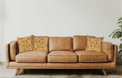 Brown leather sofa with patterned cushions against a neutral wall.