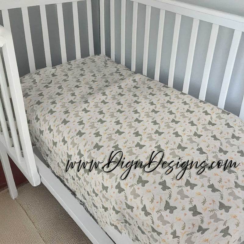 Crib with a fitted sheet featuring butterfly patterns against a striped wall.