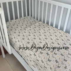 Crib with a fitted sheet featuring butterfly patterns against a striped wall.