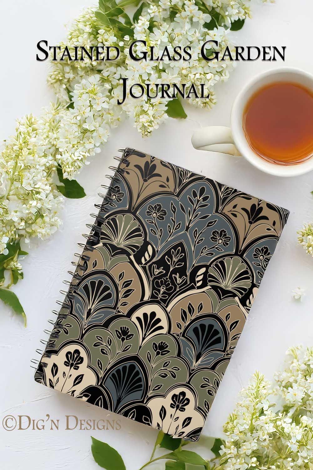 Decorative journal with floral design on cover, surrounded by white flowers and a cup of tea.