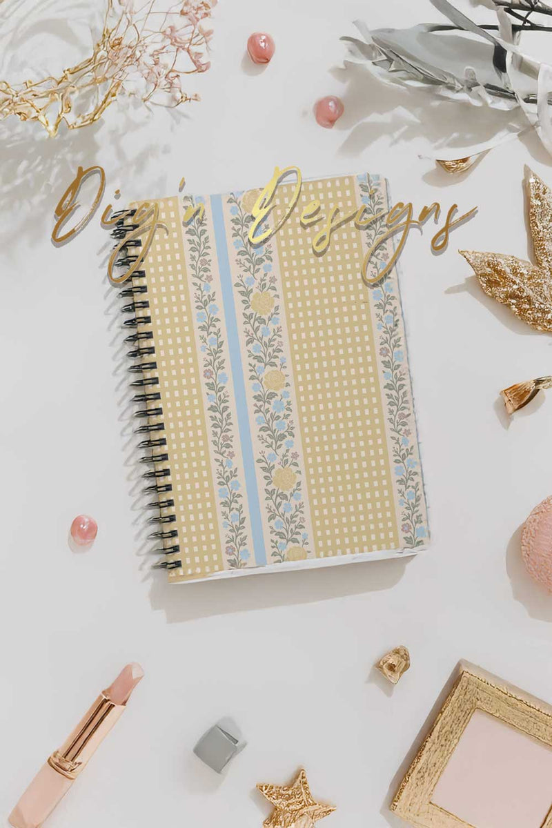 Decorative notebook with gold and blue patterns on a white surface with decorative items.