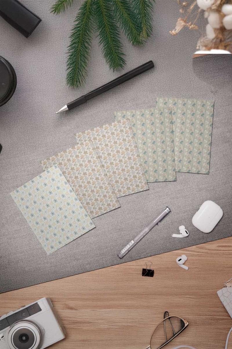 Desk with patterned paper sheets, a pen, camera, and other office supplies on a gray surface.