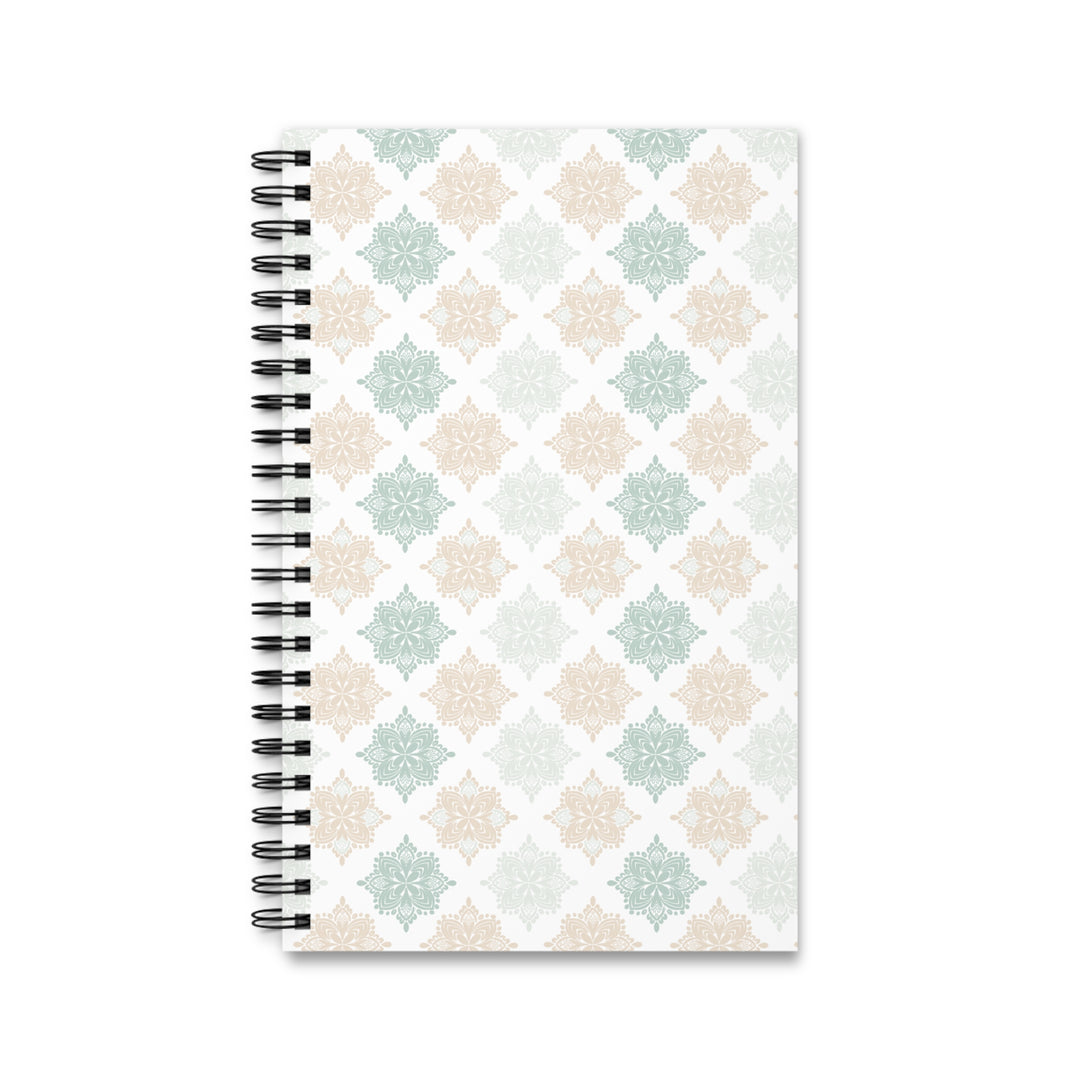 A spiral-bound notebook with a white cover featuring a repeating geometric pattern in soft sage green, beige, and light gray, bound with a black wire coil on a white background.
