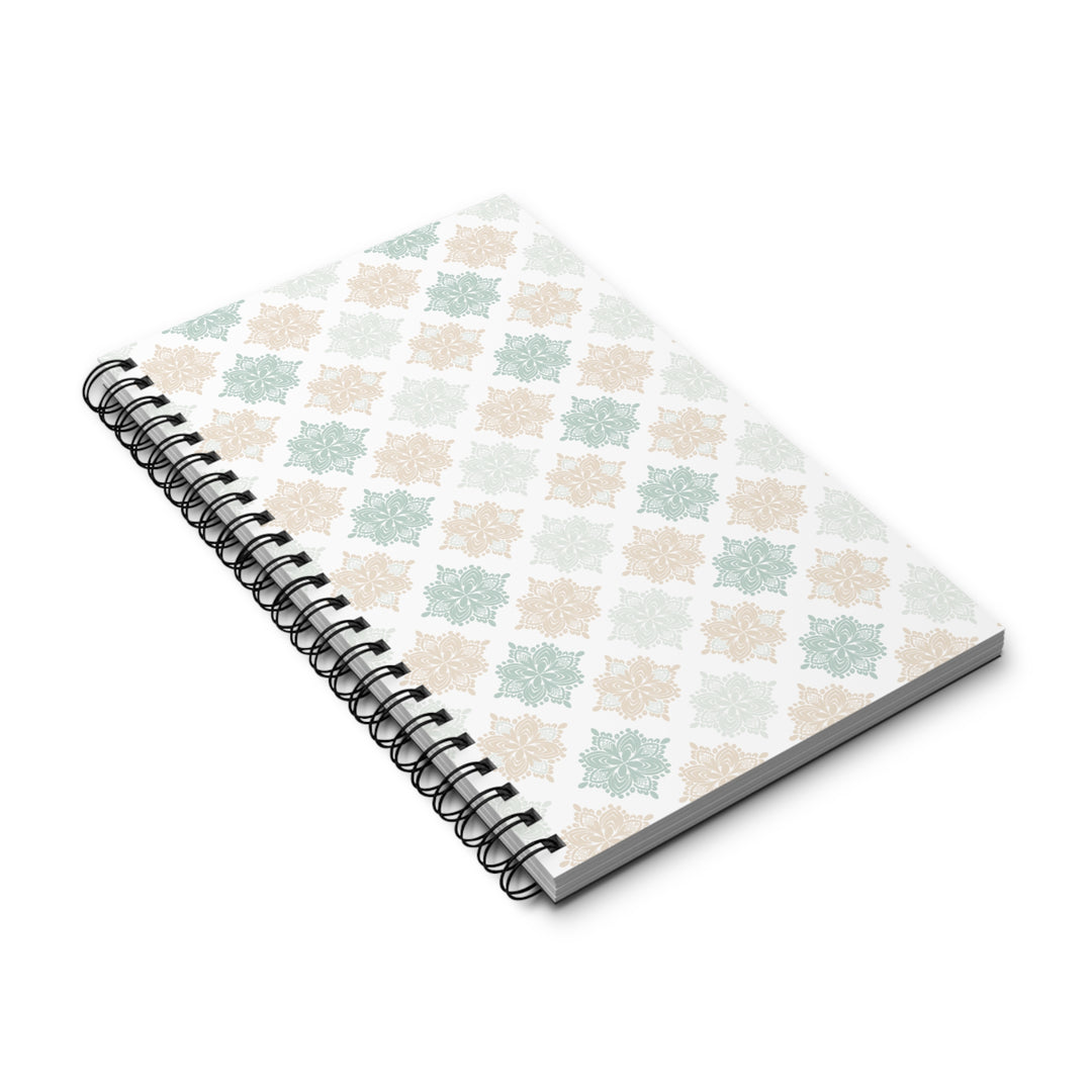 A spiral-bound notebook with a white cover featuring a repeating geometric lattice pattern in soft sage green and beige, shown on a clean white background.