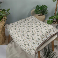 Floral-patterned blanket on a table with plants in the background