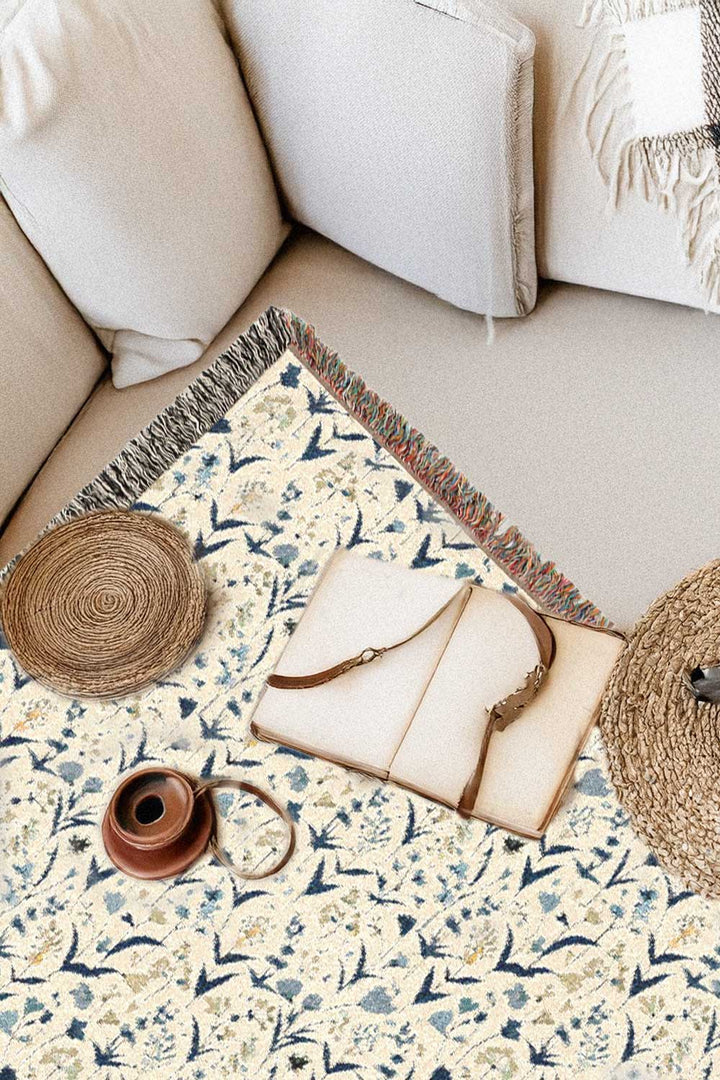 Floral-patterned rug with a notebook and decorative items on a beige sofa.