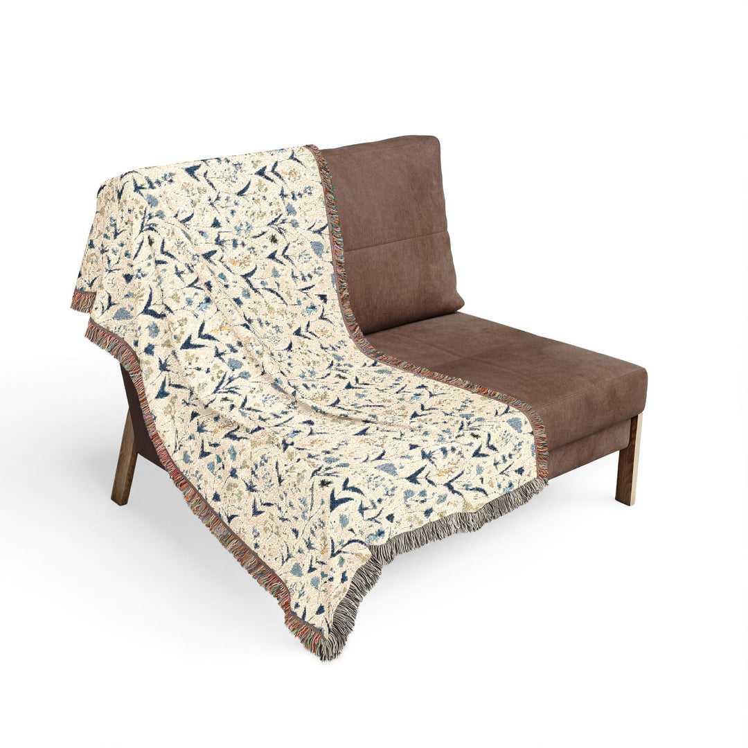 Floral-patterned throw blanket draped over a brown chair on a white background
