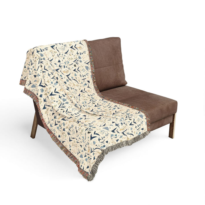 Floral-patterned throw blanket draped over a brown chair on a white background