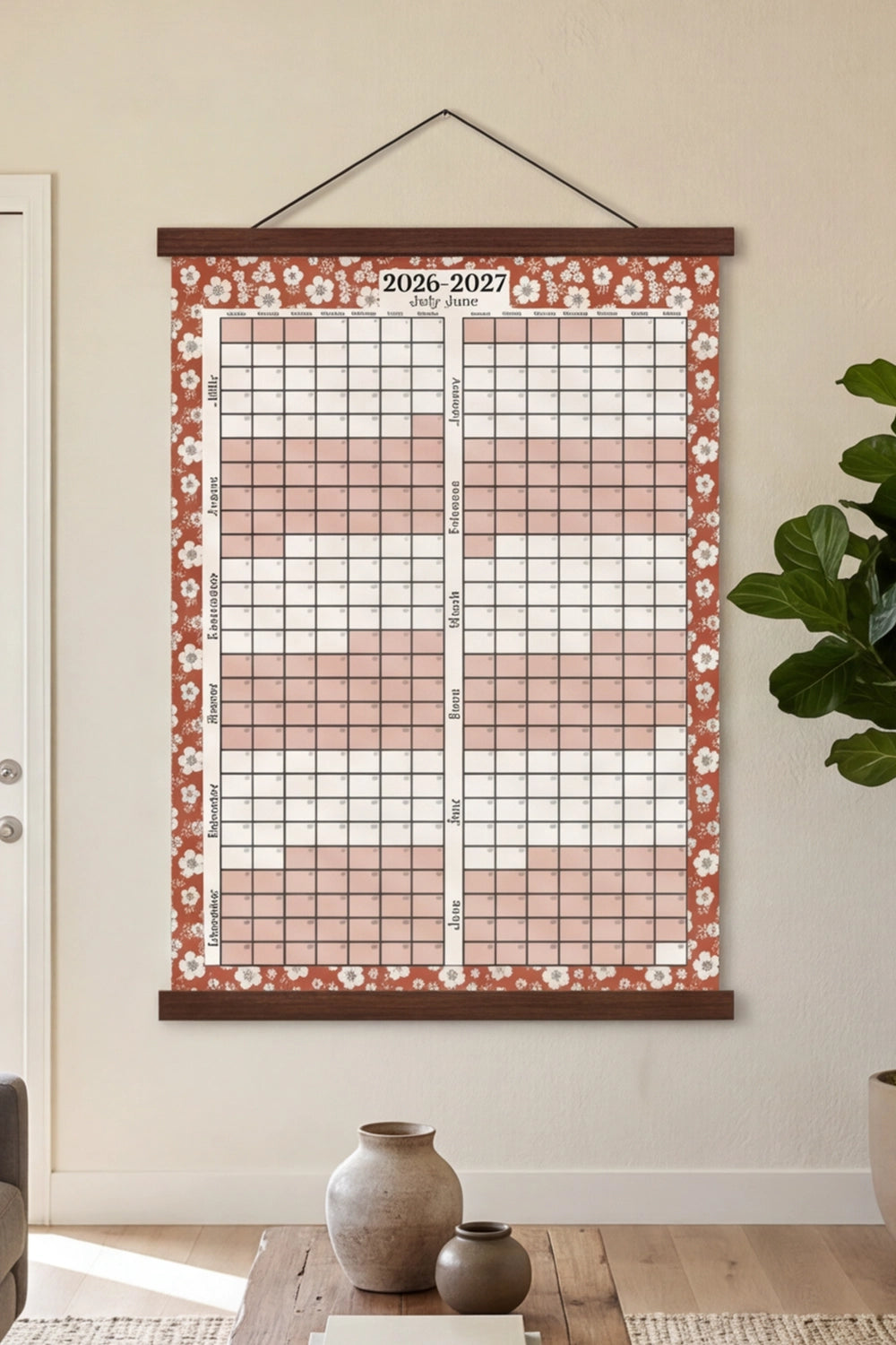 Floral-patterned wall calendar hanging on a wall in a room with decor elements.