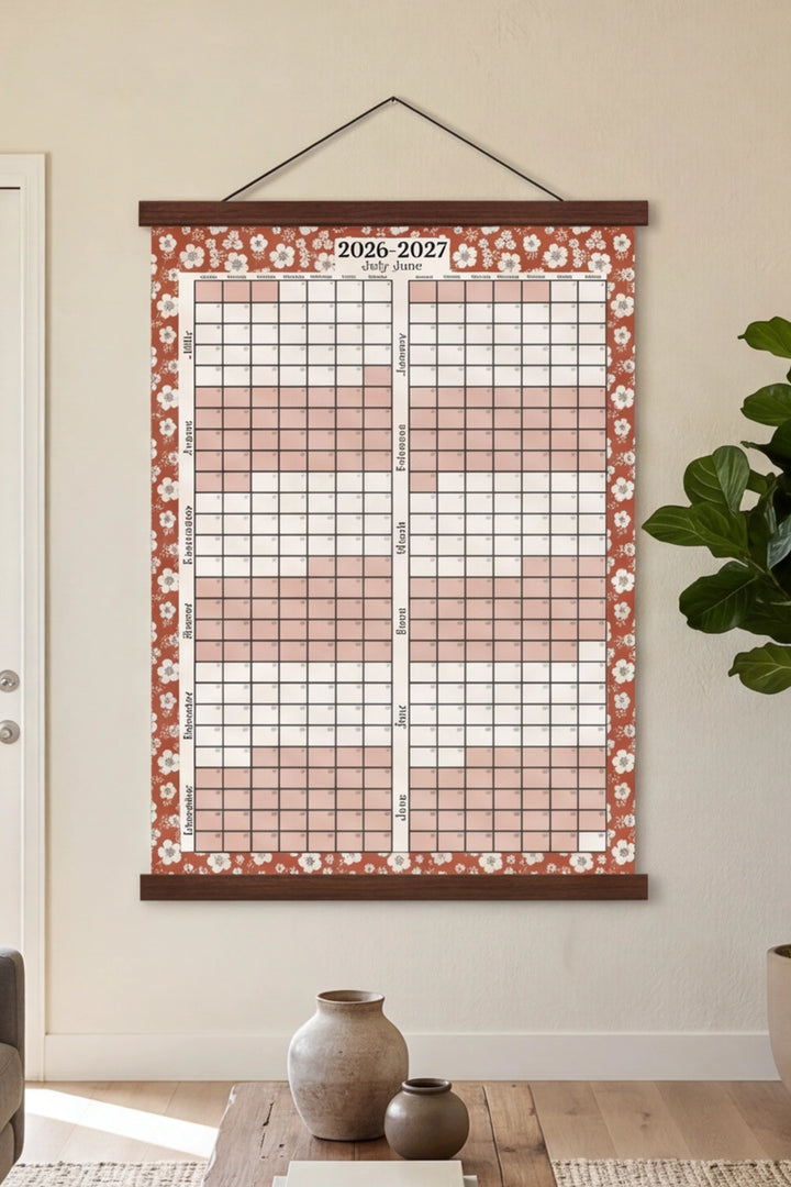 Floral-patterned wall calendar hanging on a wall in a room with decor elements.