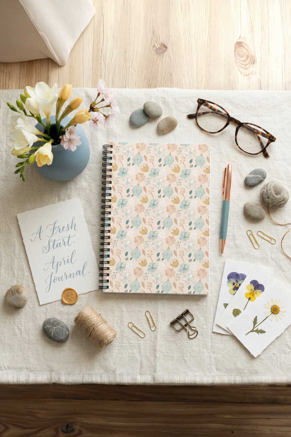Floral notebook on a wooden surface with stationery items