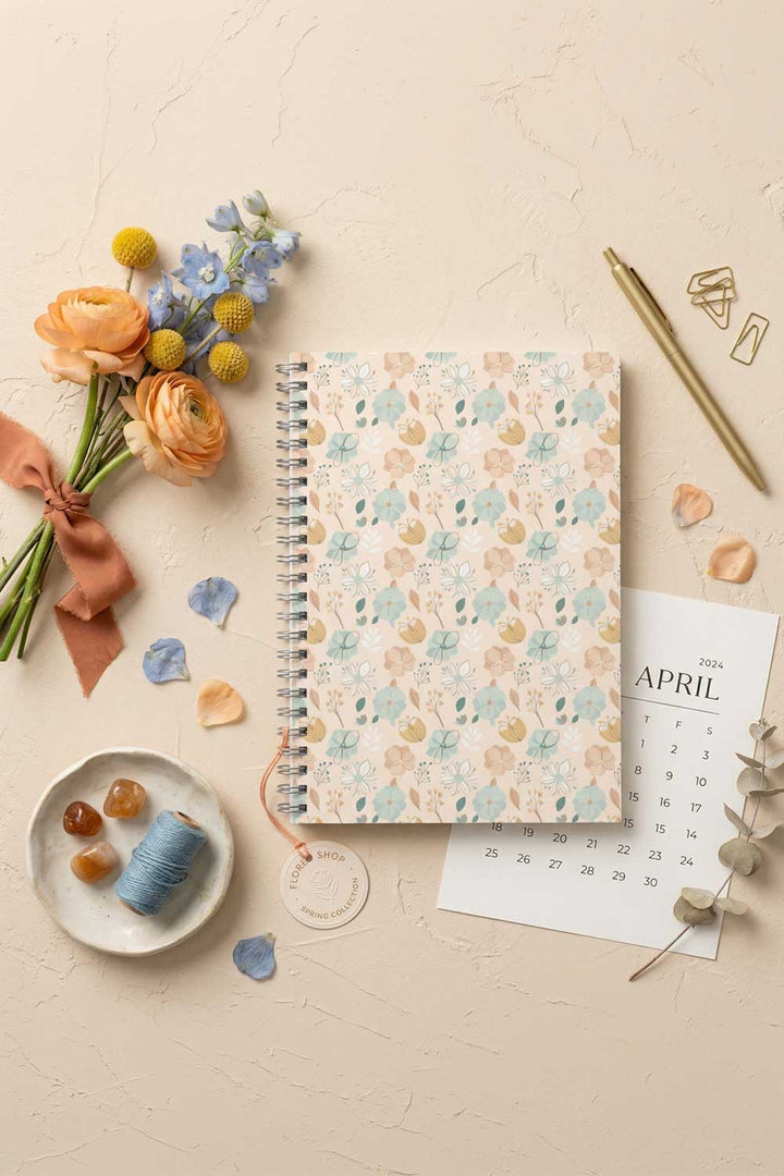 Floral notebook with stationery items on a light surface