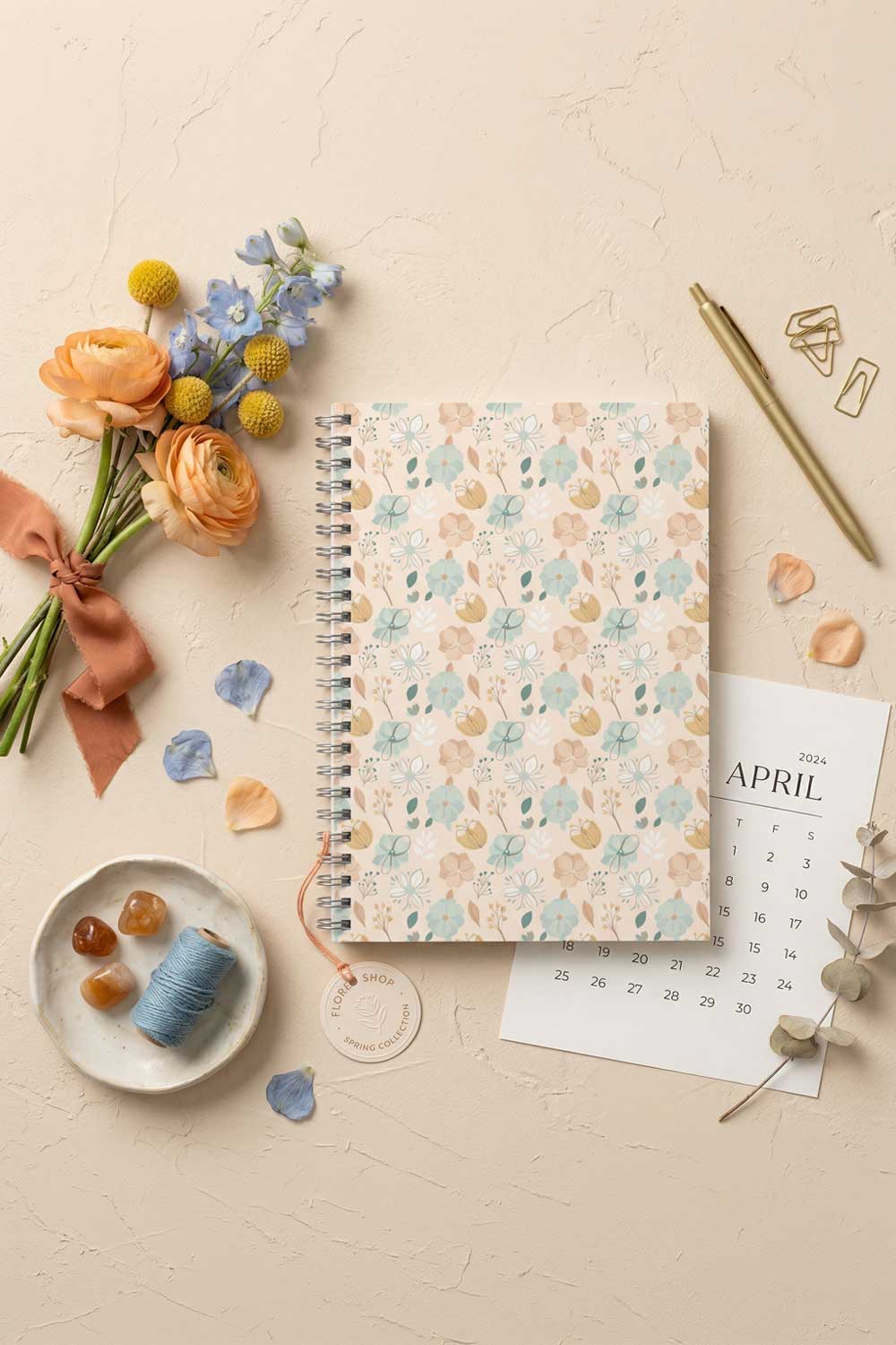 Floral notebook with stationery items on a light surface