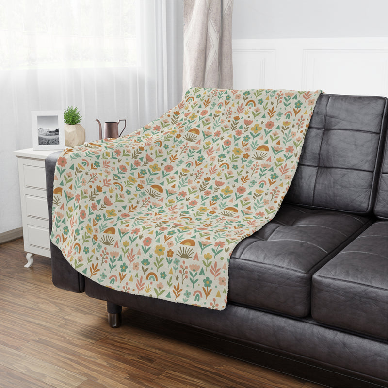 Floral patterned blanket draped over a gray sofa in a living room setting.