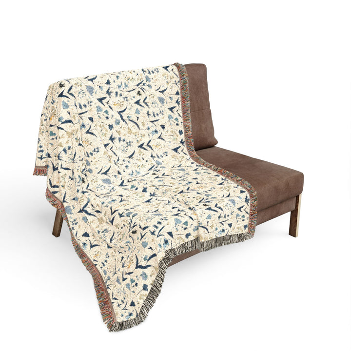 Floral patterned throw blanket draped over a brown chair on a white background