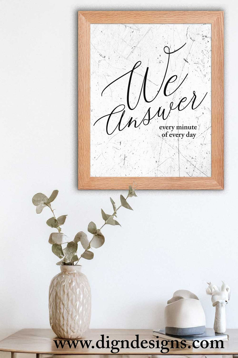 Framed artwork with 'We Answer every minute of every day' text on a white wall with decor items below.