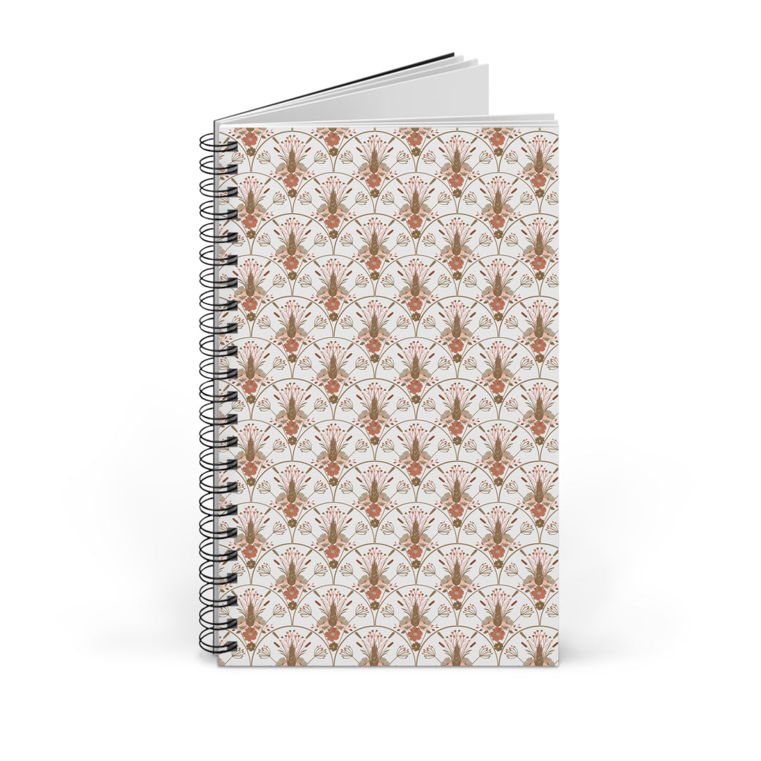 A spiral-bound notebook with a white cover featuring a repeating Art Deco style pattern in terracotta orange and muted brown, shown on a clean white background.