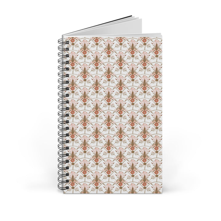 A spiral-bound notebook with a white cover featuring a repeating Art Deco style pattern in terracotta orange and muted brown, shown on a clean white background.