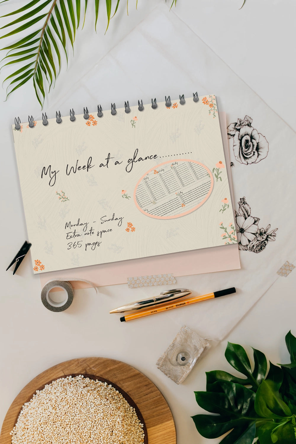 Notebook titled 'My Week at a Glance' on a desk with stationery items and plants.