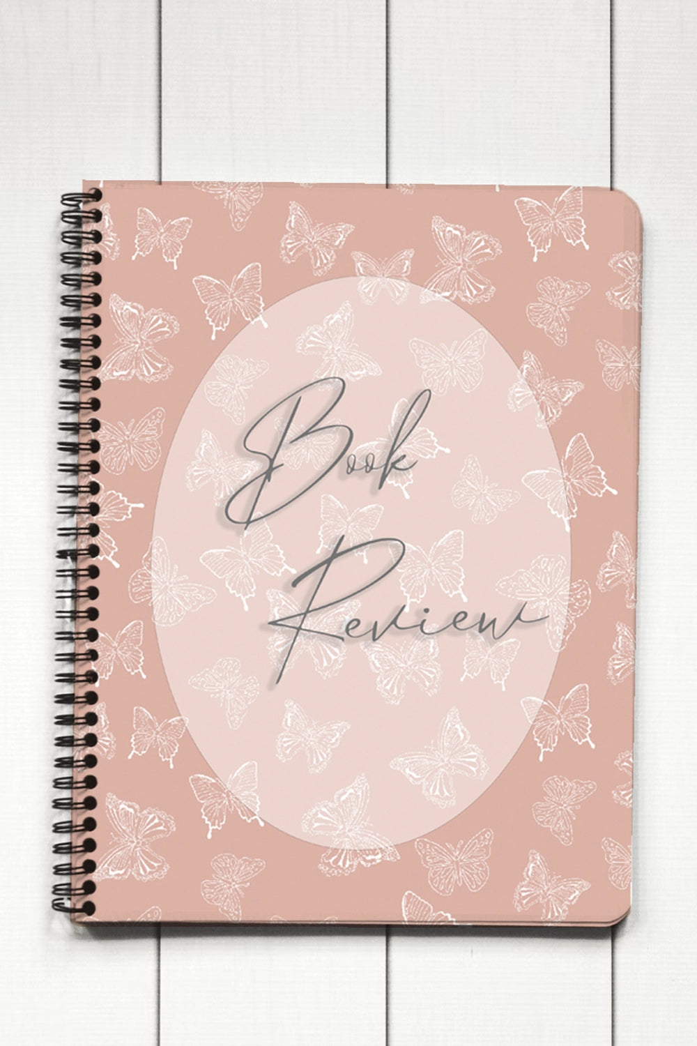 Notebook with 'Book Review' text and butterfly pattern on a wooden surface