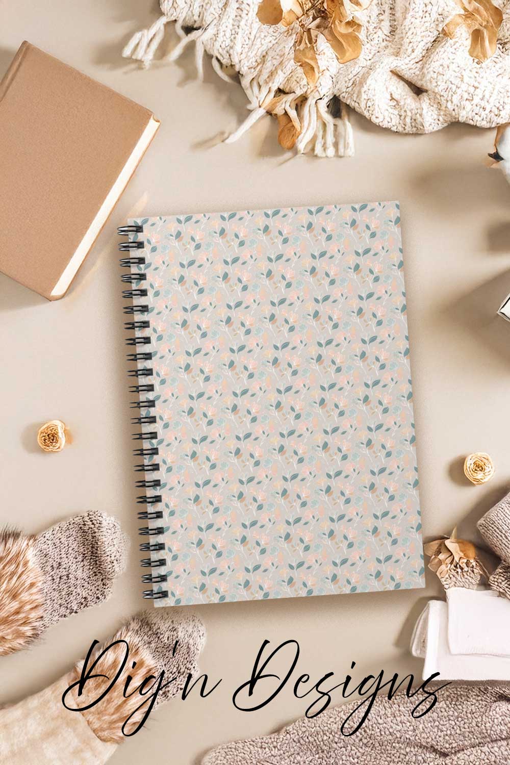 Notebook with a floral pattern on a beige surface with decorative items.