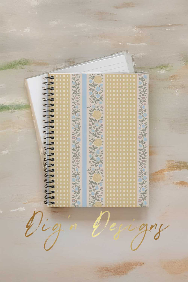 Notebook with decorative cover on a textured surface, featuring the brand 'Digi'n Designs'.