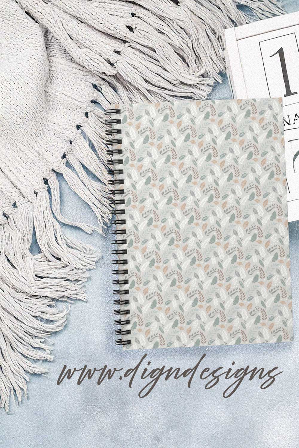 Notebook with floral pattern on a textured surface, featuring the brand &