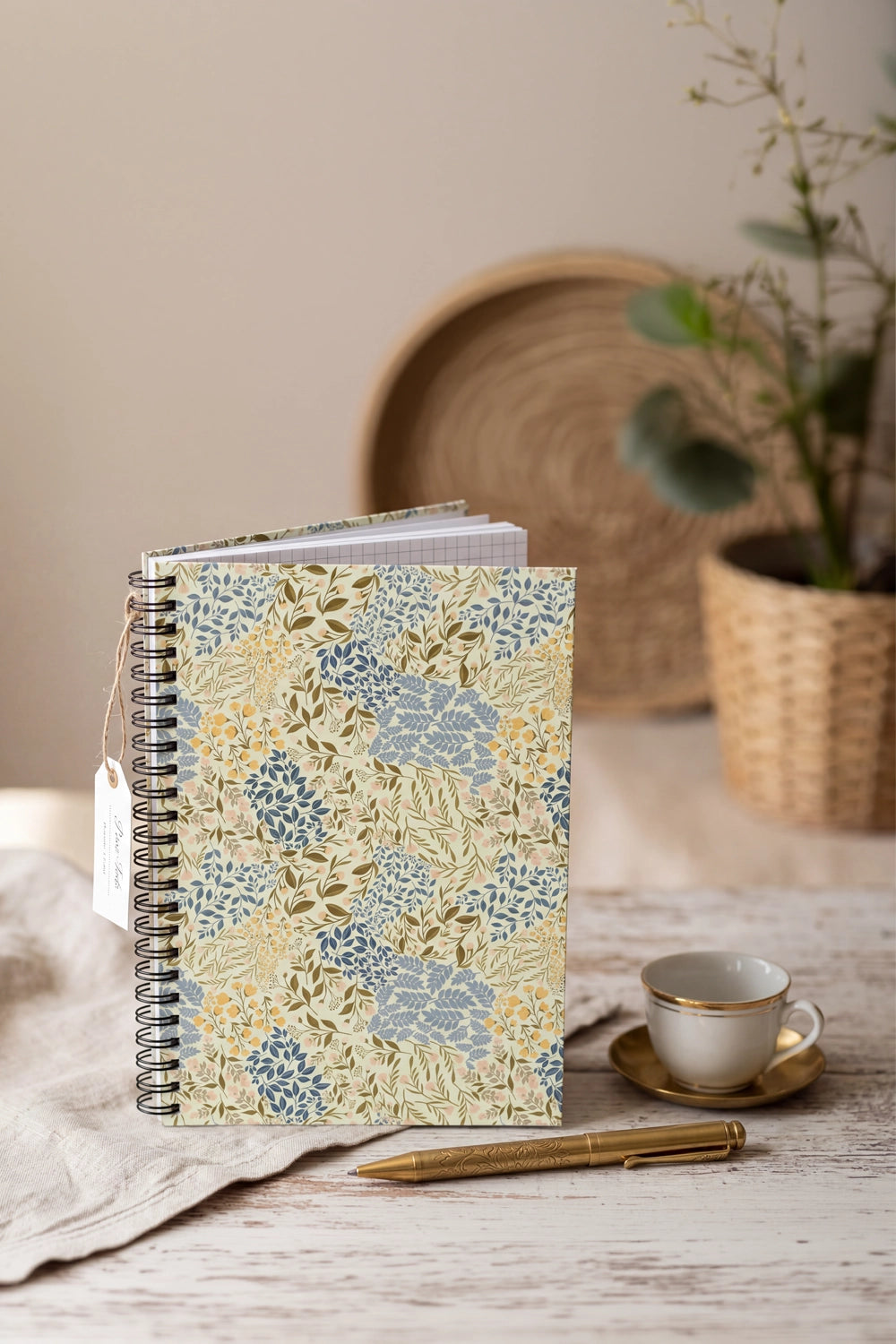 Notebook with floral pattern on a wooden table with a cup and pen