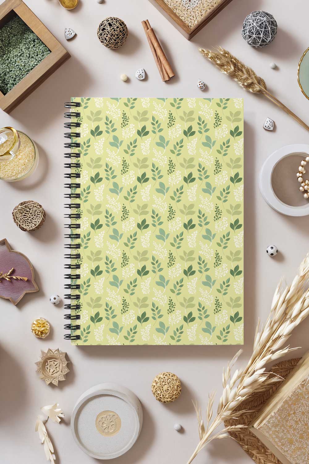 Notebook with green leaf pattern on a decorative surface with small objects