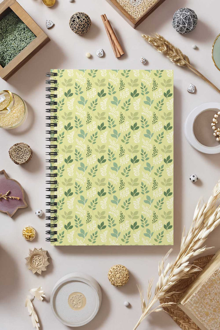 Notebook with green leaf pattern on a decorative surface with small objects