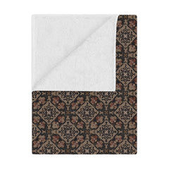 Patterned blanket with white center and brown geometric border on a white background