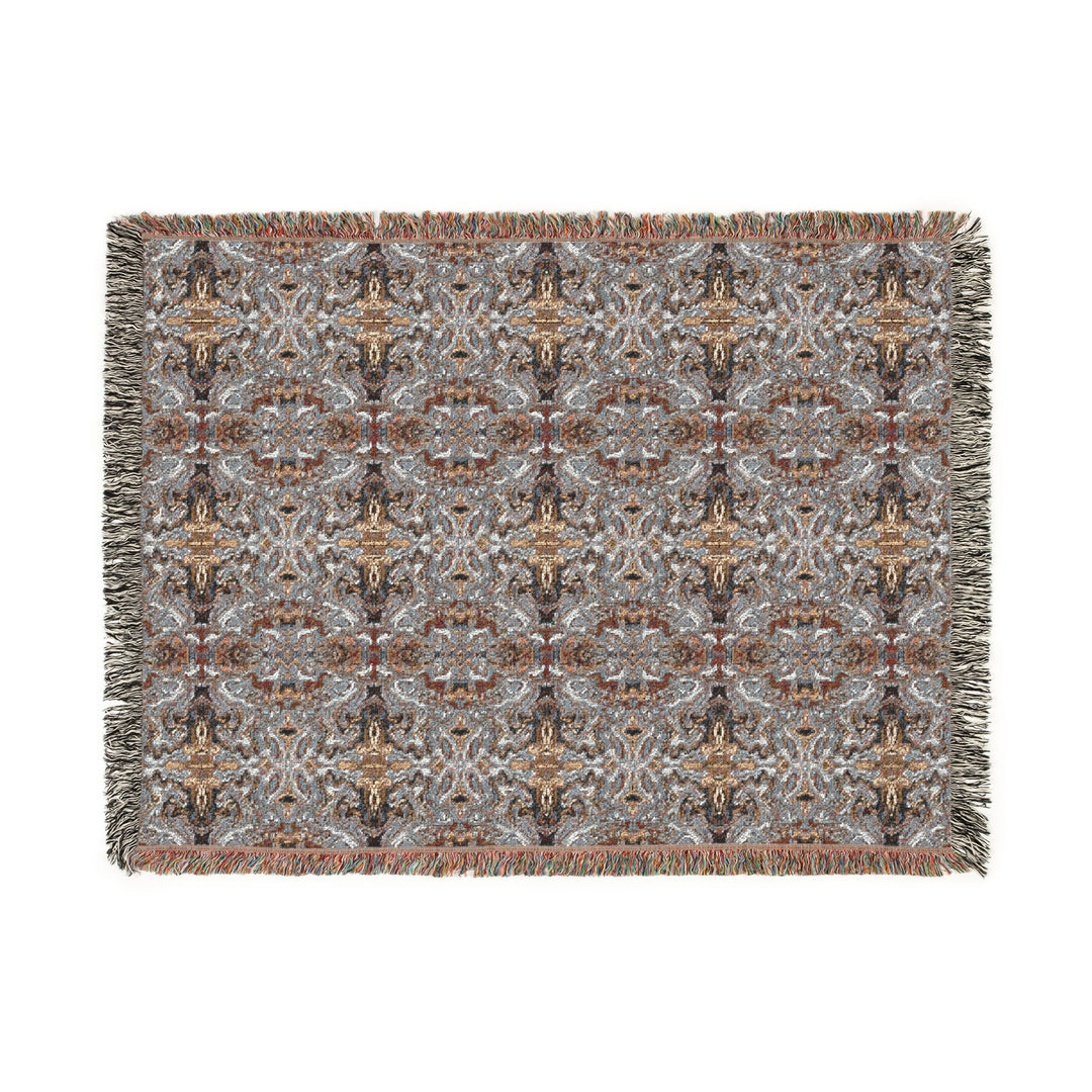 Patterned woven blanket with fringes on a white background