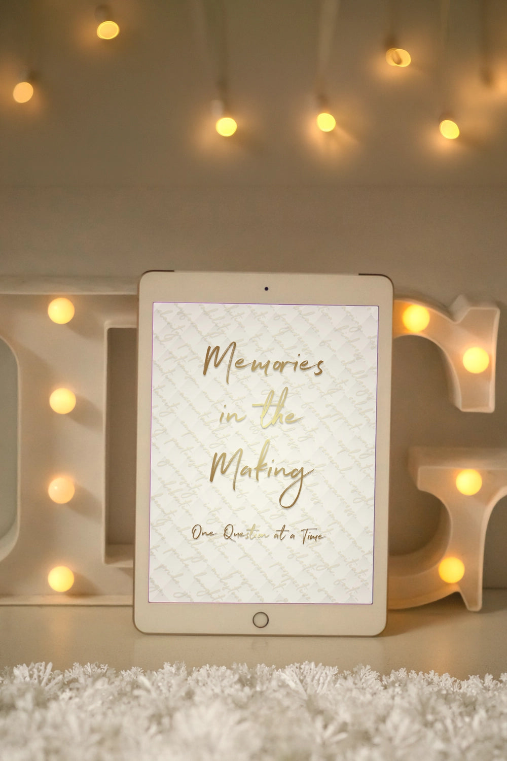 Tablet with 'Memories in the Making' text on a decorative setup with lights