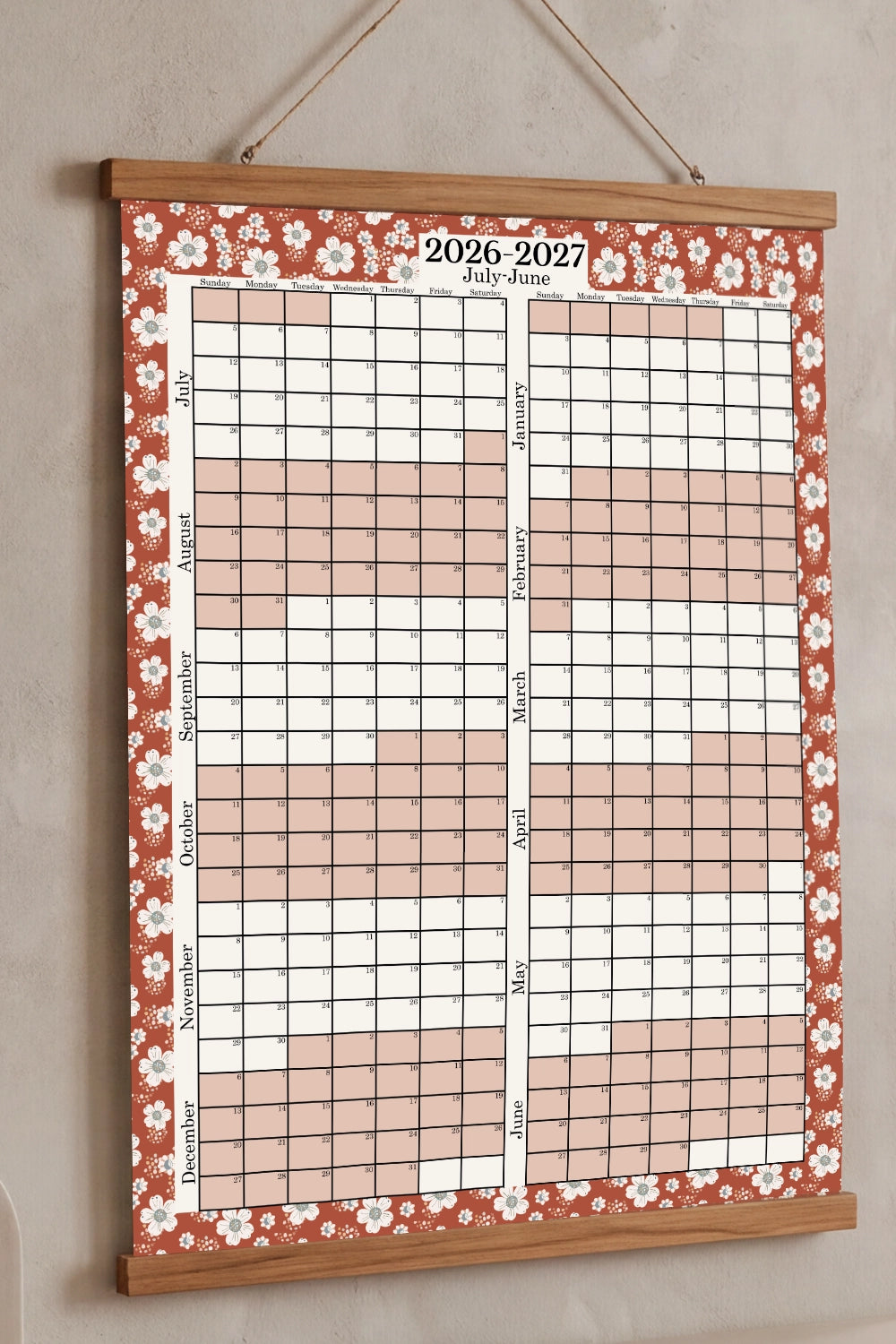 Wall calendar with floral design for 2026-2027 on a beige wall.