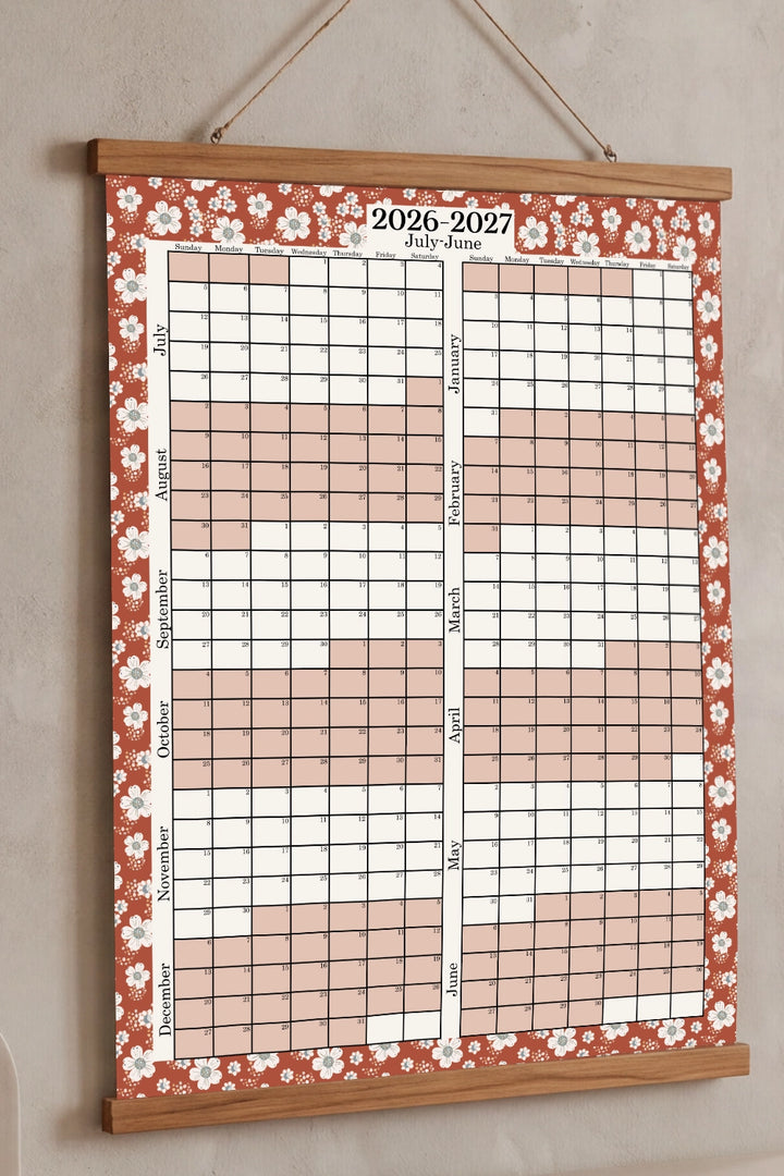 Wall calendar with floral design for 2026-2027 on a beige wall.